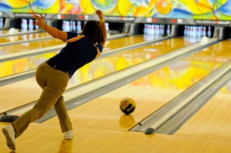 Female Bowler Just Releasing Bowling Ball Down Alley